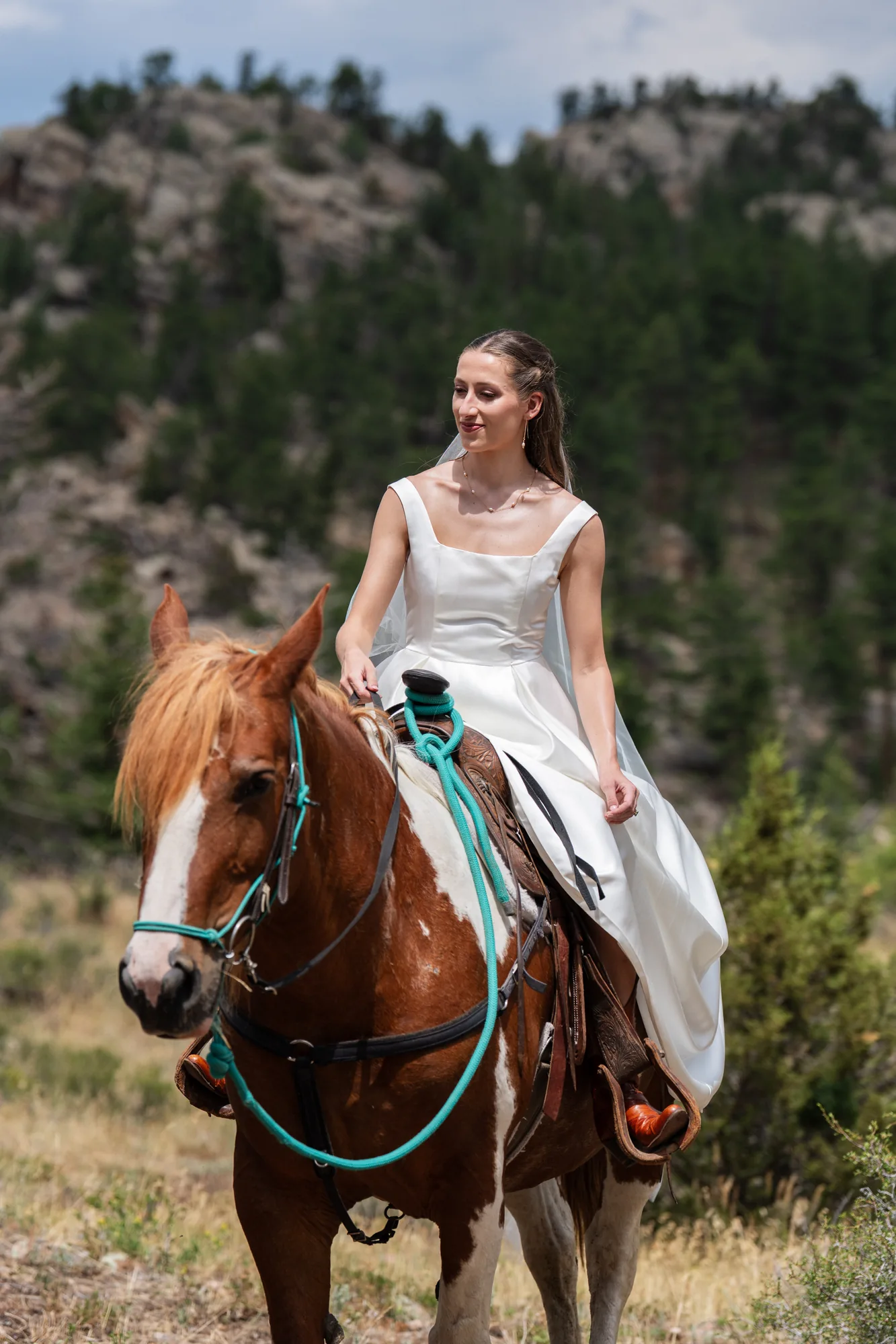 Bride riding a horse through the mountain landscape near Red Feather Lakes, Colorado