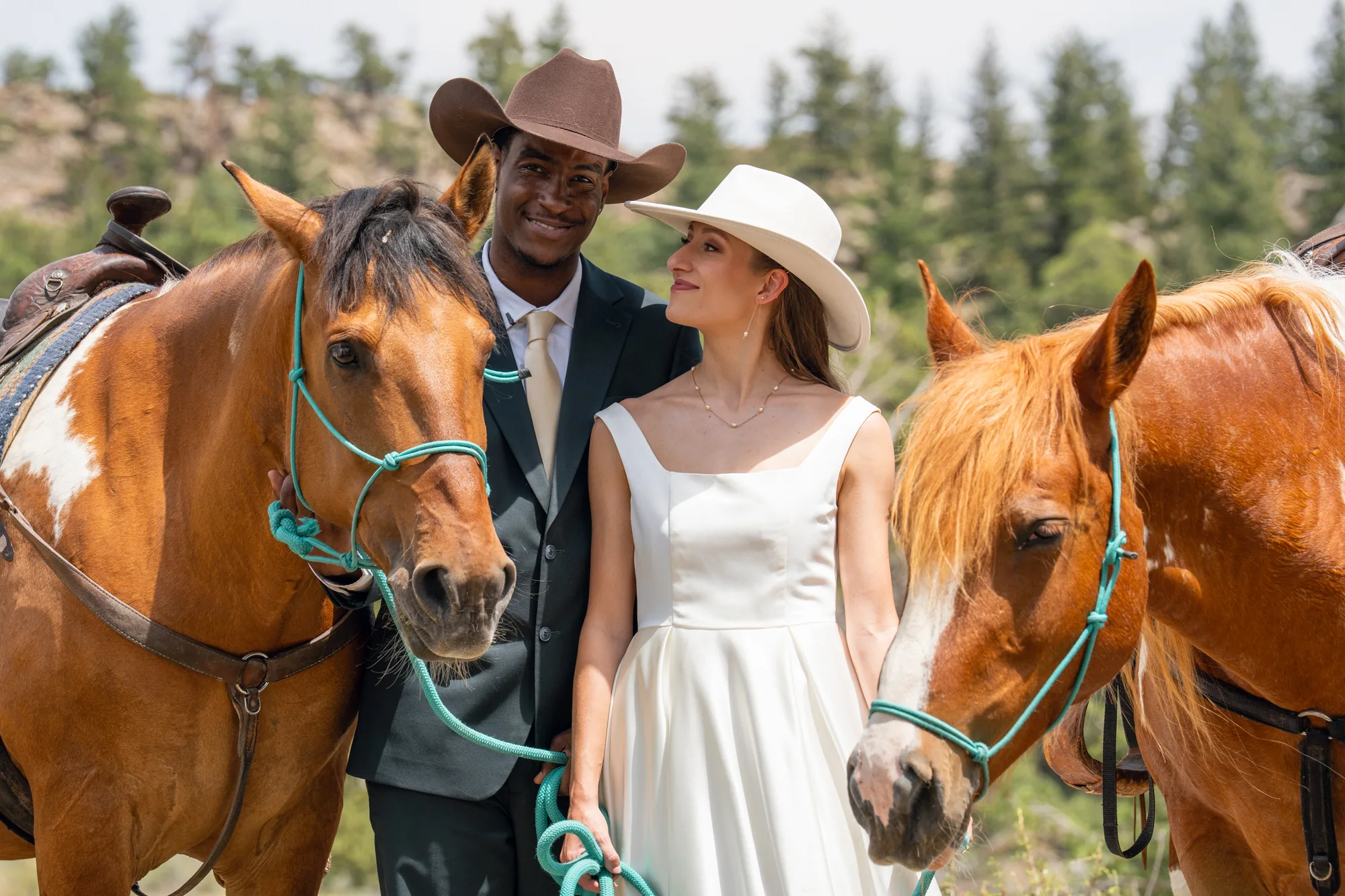 Isabella and Tim standing between their horses after their Sundance Trail Guest Ranch elopement