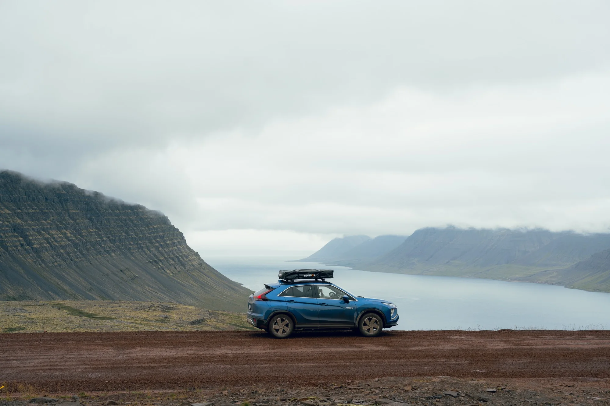 SUV with a rooftop tent stopped beside a dramatic Icelandic fjord while scouting wedding portrait locations